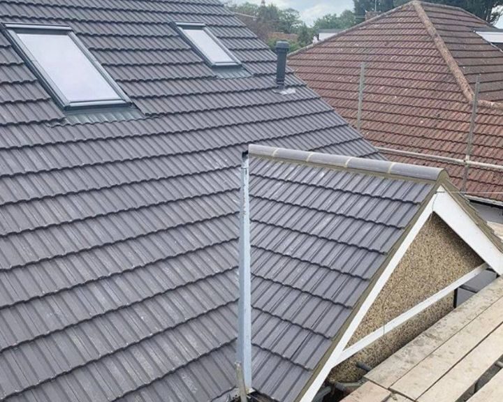 A new pitched roof with grey tiles installed on a house.