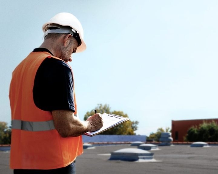 A roofer carrying out a thorough roof inspection on a commercial roof in Gosport.